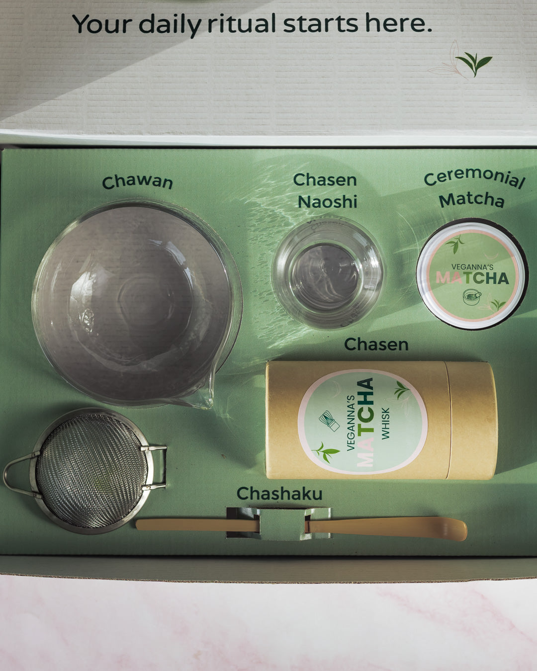 Tea-making set with Chawan, Chasen, Naoshi, Ceremonial Matcha, Chasen, and Chashaku on a green background.